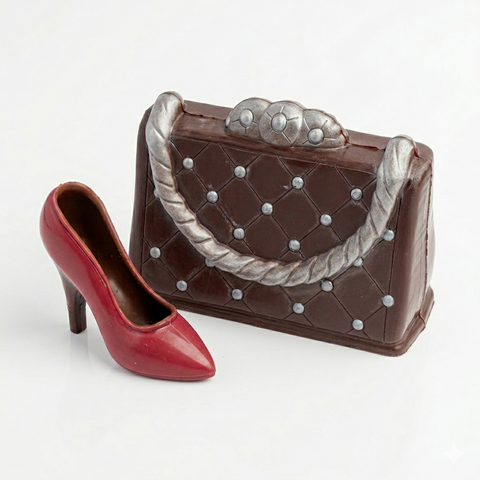 Chocolate handbag with silver studs and a red high heel shoe on a white background