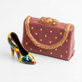 Colorful high-heeled shoe and pink handbag with gold accents on a white background
